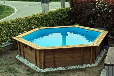 Piscina in legno da giardino Jardin 434 installata in giardino con ghiaia decorativa e luci LED per un effetto elegante anche di sera. Perfetta per spazi residenziali.