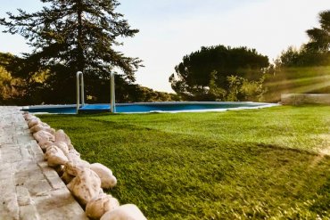 Piscina in acciaio fuori terra WHITE POOL 490x360x130 cm, installata su prato, in stile buca da golf, e circondata da aiuole decorative. Soluzione ideale per chi cerca una piscina resistente e facile da integrare in ogni spazio esterno. Perfetta per il relax estivo e per arredare con stile il proprio giardino.