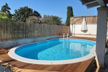 Piscina in acciaio fuori terra con bordo bianco, perfetta su terrazza in legno per un giardino raffinato. Facile da installare, resistente e ideale per relax e divertimento in famiglia. Dona valore al tuo spazio esterno con una piscina elegante e funzionale.