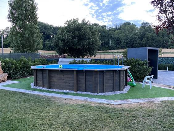 Piscine de jardin en bois JARDIN 607, installée dans un jardin soigné, avec pelouse verte et espace détente parfaitement intégré à l’environnement.