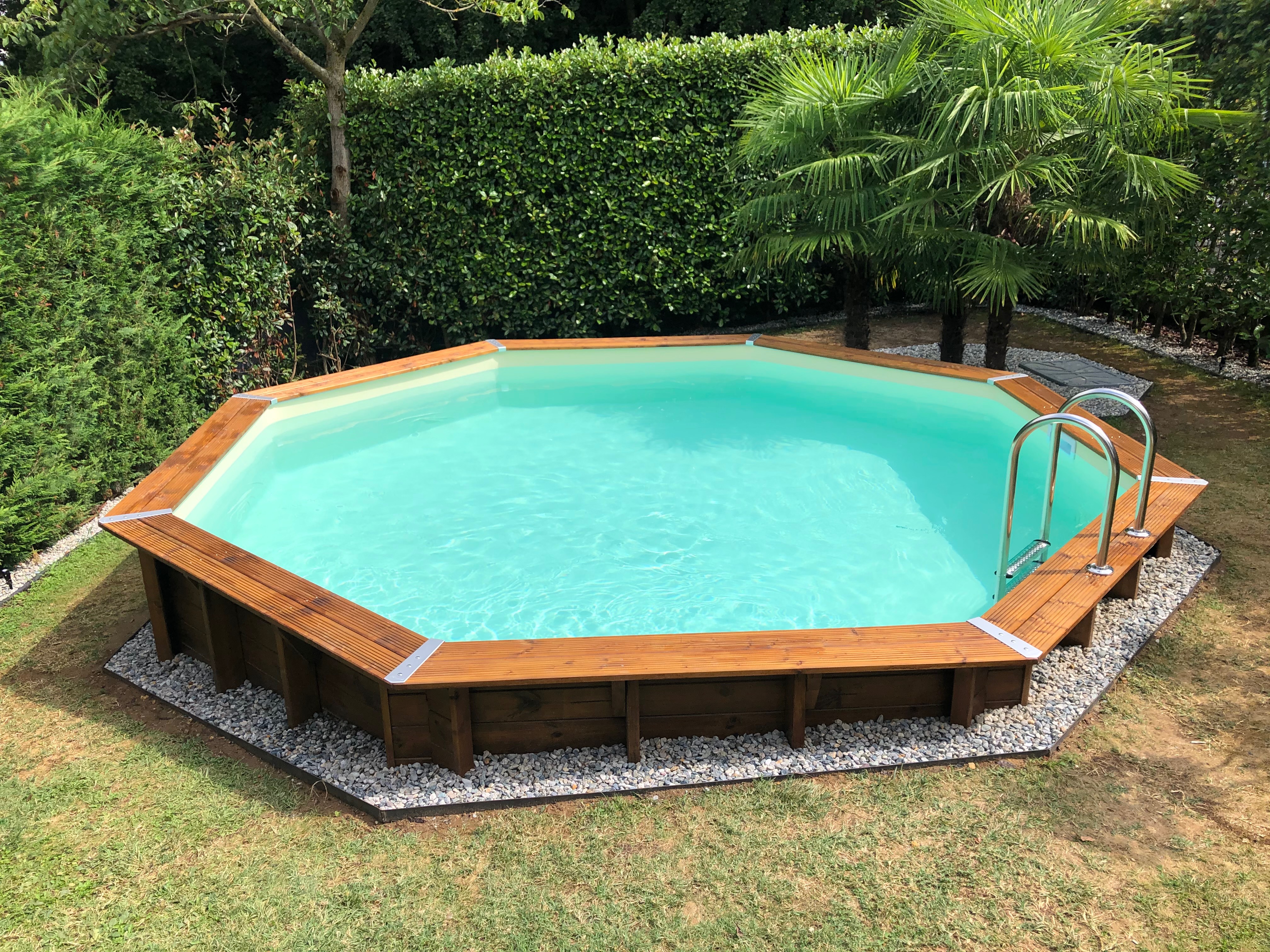 Piscine de jardin en bois Ocean 580, parfaitement intégrée dans le jardin, entourée de pelouse verte et d’espaces de détente, pour des moments agréables en plein air.